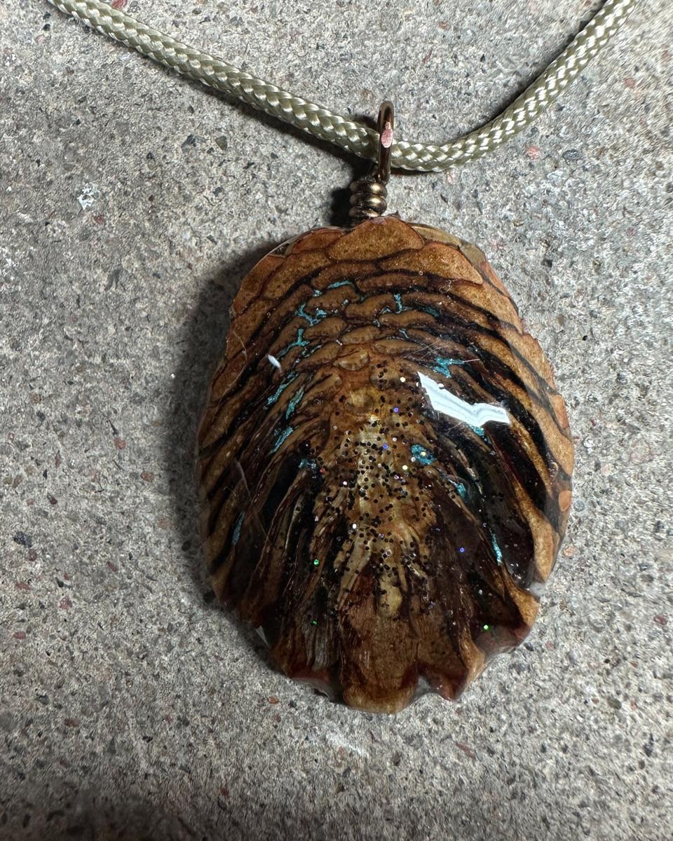 Close view of turquoise lines running through the gaps between tan scales with dark glitter down the middle