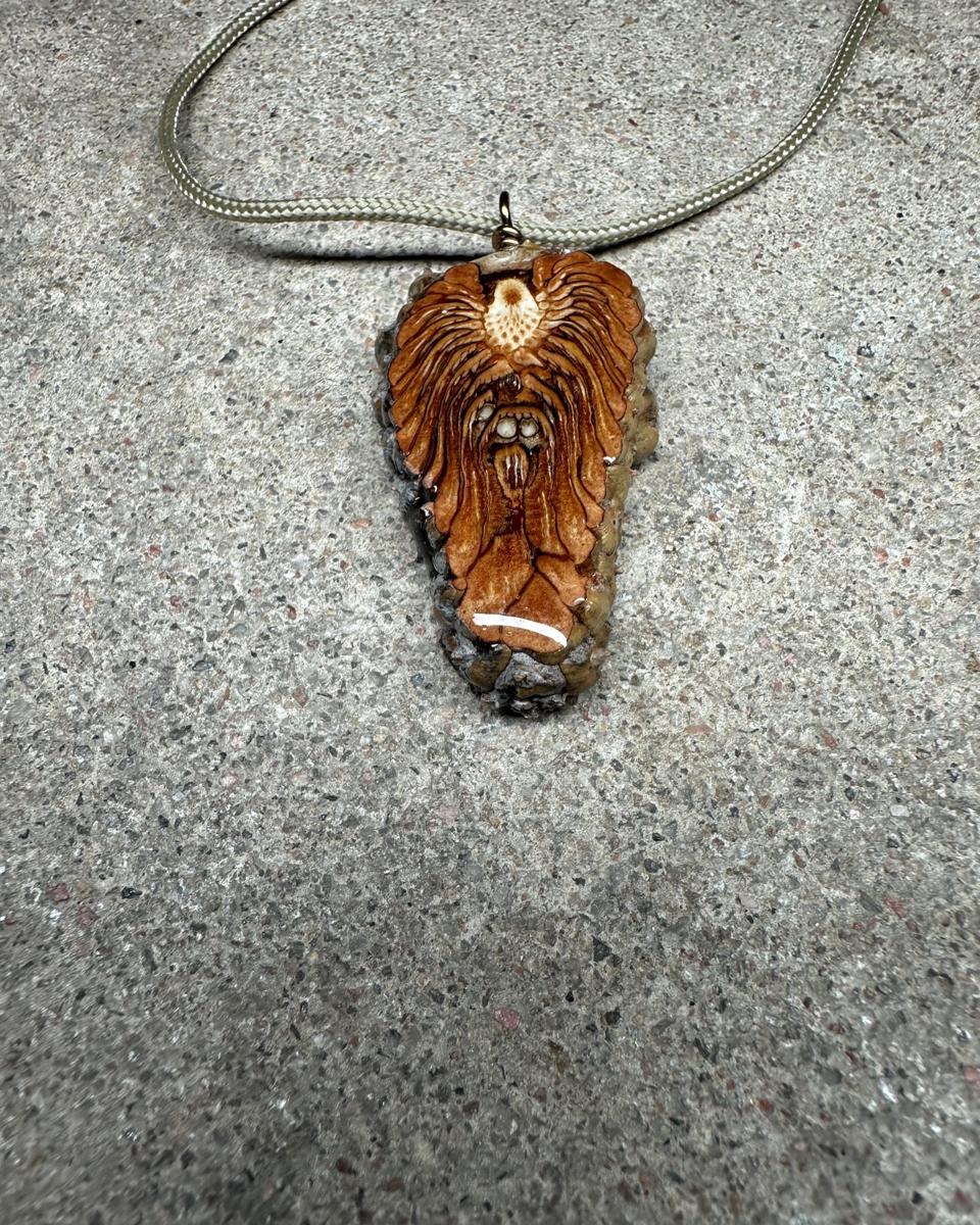 Closer view of the pendant on its cord, cream core with rust rays fanning down into arcs and glossy resin over the whole cut face