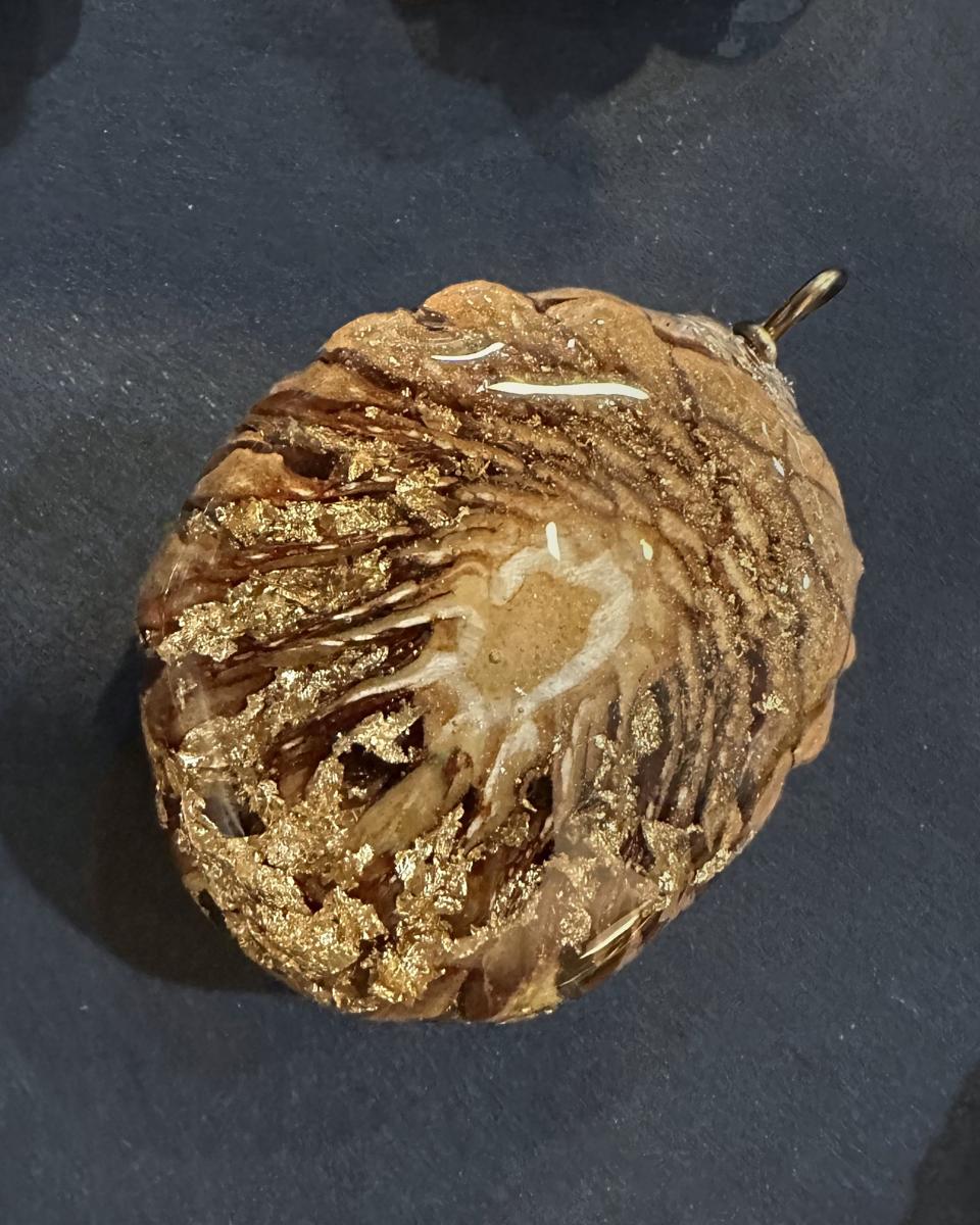 Round pine cone pendant with gold leaf flakes suspended in clear resin