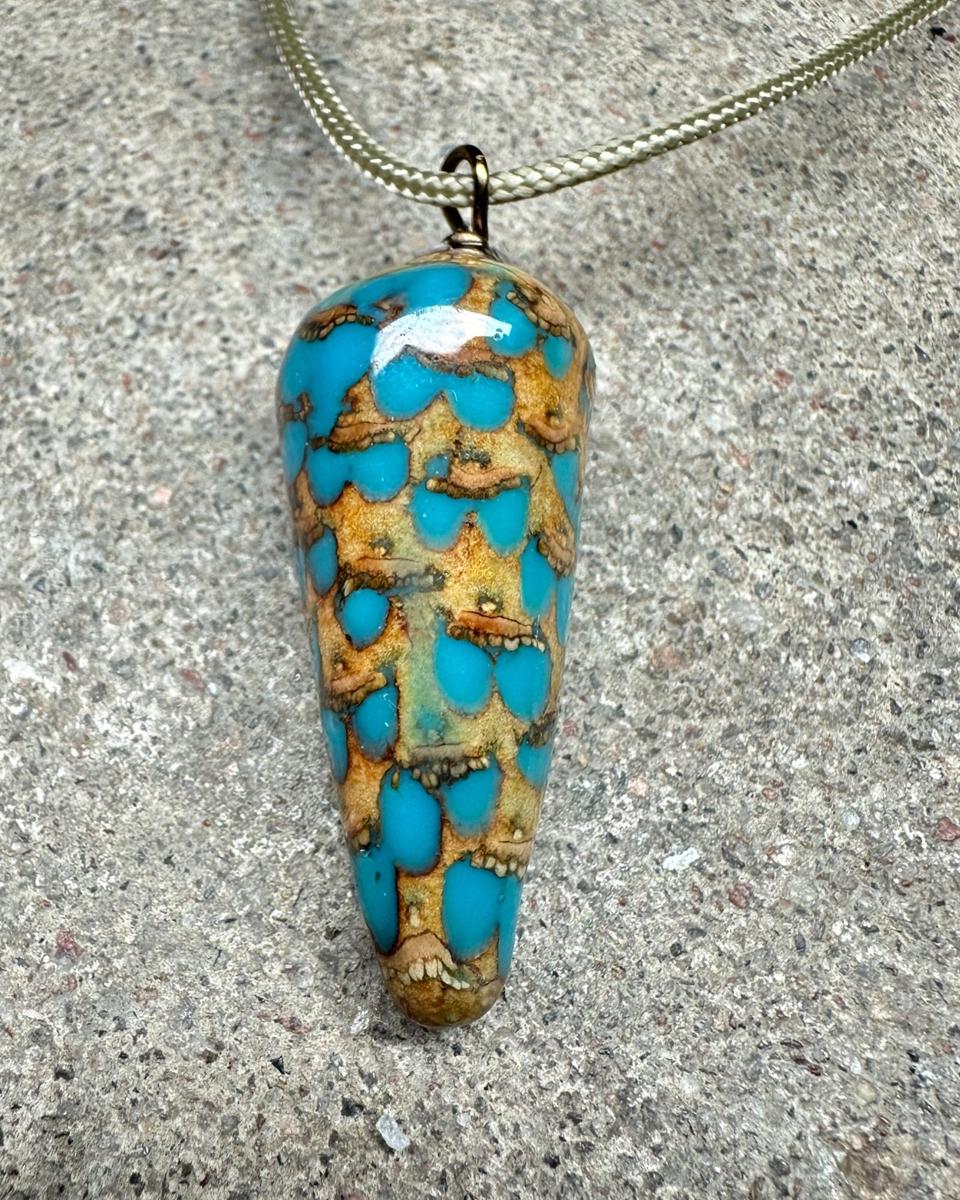 Close view of staggered tan scales with turquoise drops filling the gaps between them