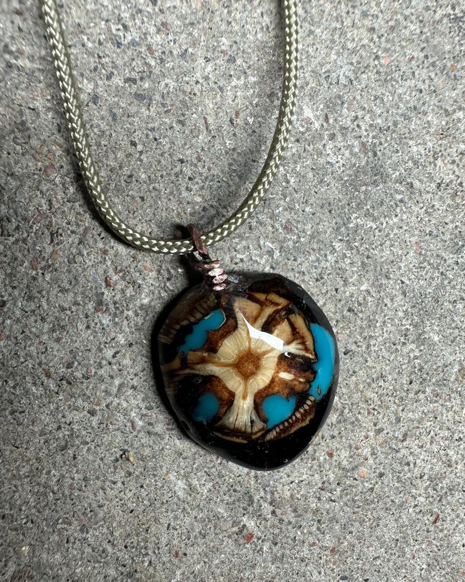 Closer view of the same pendant, showing the cream star, brown scale rings and turquoise patches under glossy resin