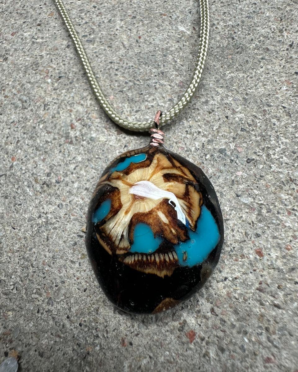 The pendant at an angle, with a wide turquoise pool at the lower right and the copper loop at the top
