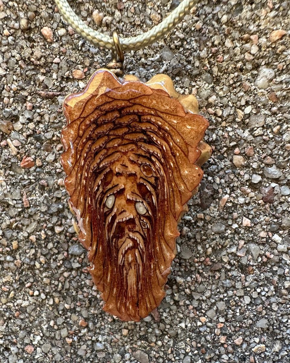 Close view of stacked rust and tan arcs with pale flecks along the ridges under glossy resin